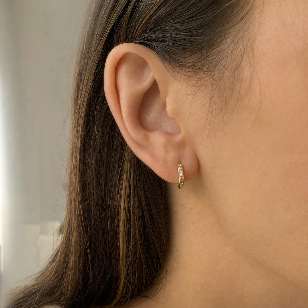 Woman wearing 14K yellow gold CZ huggie hoop earrings, model image for illustration