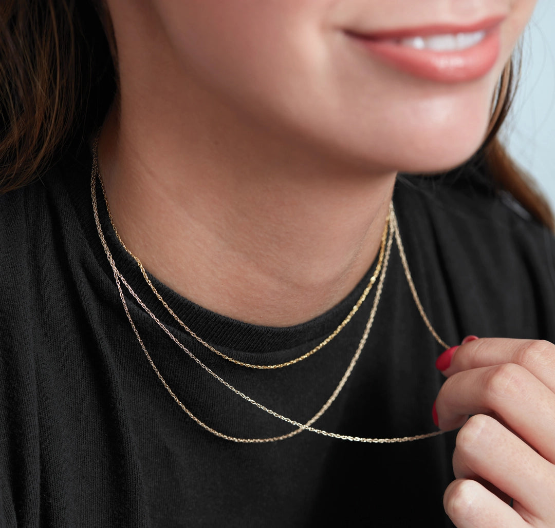 Woman wearing layered delicate gold chain necklaces Silvadi Aurora, CO